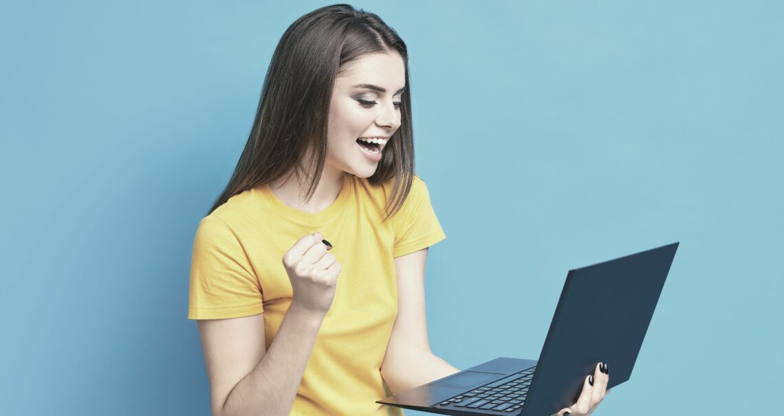 Excited Girl Receiving Messages on Laptop_von Victor Gladkov